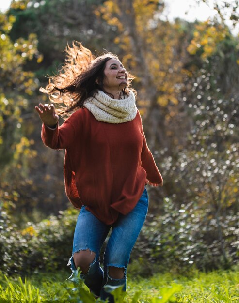 Photo woman in red sweater dancing happily on a meadow in a forest