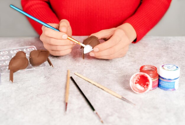 Woman in red sweater decorating chocolate bird dessert on grey stone kitchen table