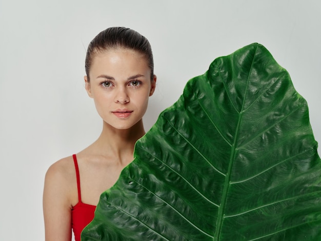 Woman in red swimsuit green palm leaf light background