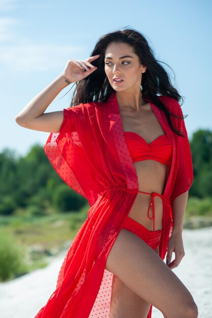 Photo a woman in a red swimsuit with a red kimono and a white hat