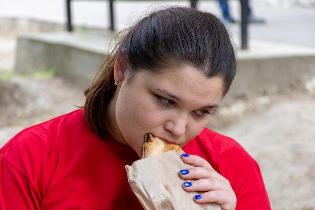 Woman in red tshirt eating bun