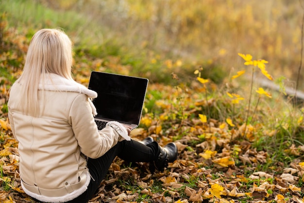 woman relaxes in park while working on her laptop