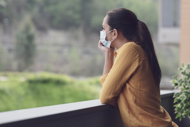 Woman relaxing on the balcony and wearing a face mask