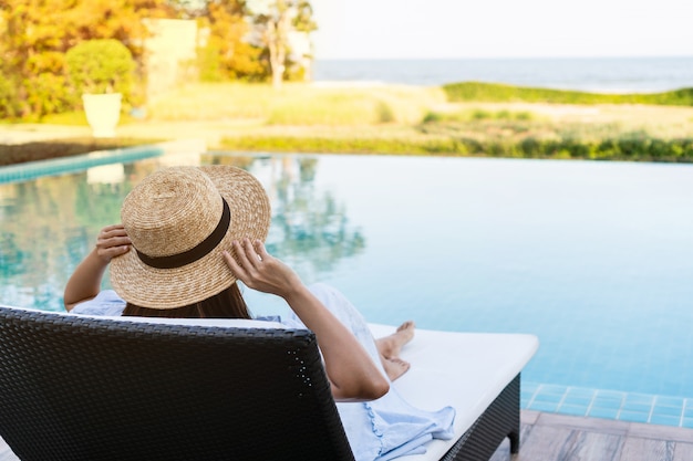 Donna che si rilassa nel bello albergo di lusso vicino alla piscina, concetto di vacanze estive.