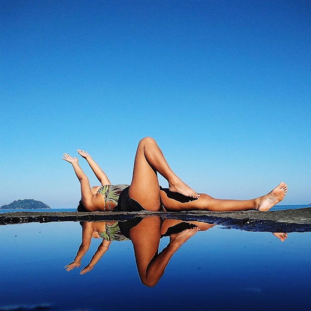 Photo woman relaxing by sea against clear blue sky