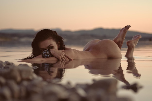 사진 해가 지는 동안 하늘을 배경으로 바다에서 휴식을 취하는 여자