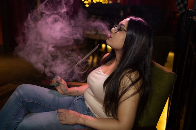 バーで水ギセルからvapingしてリラックスする女性