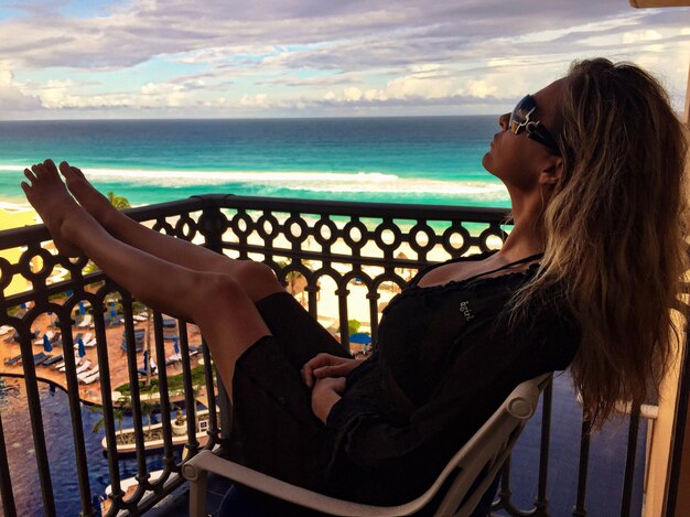 Photo woman relaxing on chair in balcony against sea