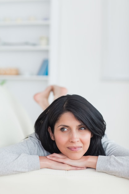 Woman relaxing on a couch holding her head with two hands