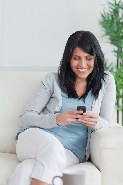 Woman relaxing on a couch while holding a phone