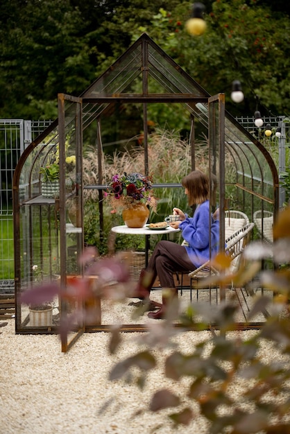 Woman relaxing in glasshouse in garden