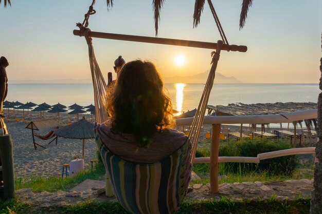 Foto donna che si rilassa in un'amaca sulla spiaggia contro il cielo