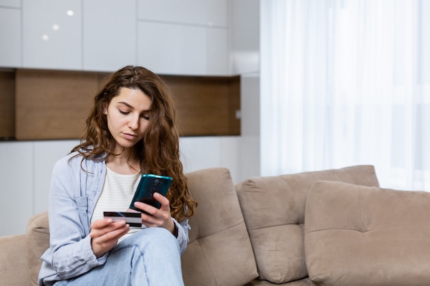 Woman relaxing at home, shopping online, using phone online shopping program and credit card