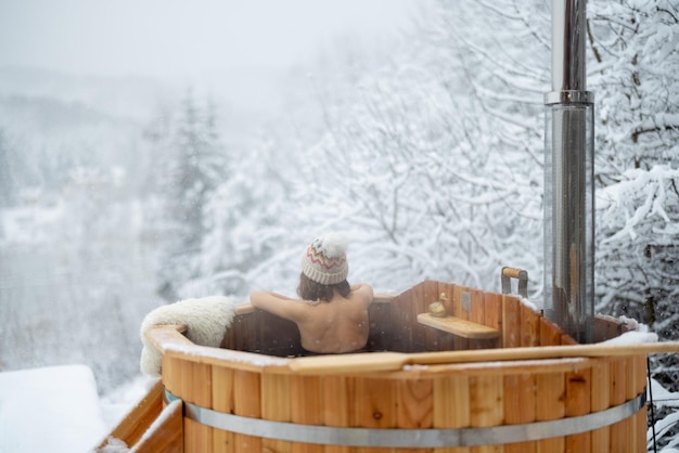 Женщина расслабляется в горячей ванне в заснеженных горах
