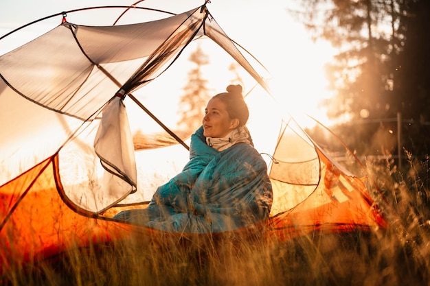 여자 휴식과 텐트에서 침낭에 누워 숲에서 일몰 캠핑 산 풍경 여행 라이프 스타일 캠핑 여름 여행 야외 모험