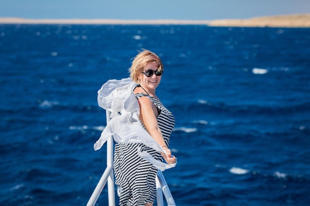 Foto donna che si rilassa sul muso dello yacht in una soleggiata giornata estiva in mare