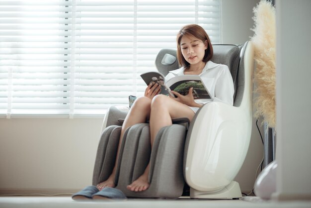 A woman relaxing and reading a book on the massage chair in the living room