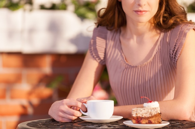 レストランでリラックスした女性。屋外カフェでコーヒーを飲む魅力的な若い女性のトリミングされた画像