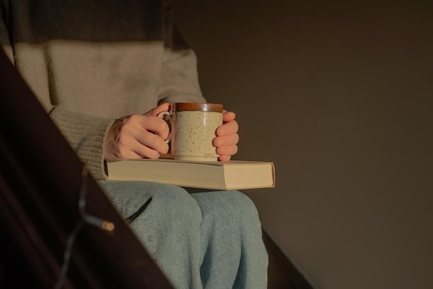 Woman relaxing on stairs in sunlight with cup and book