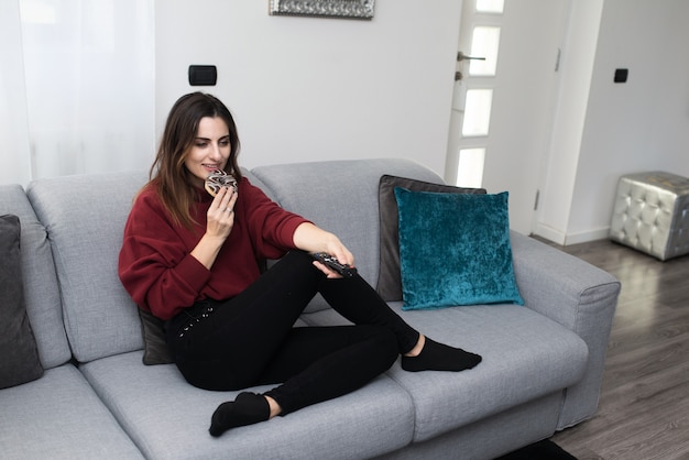 Woman relaxing while eating a donut at home