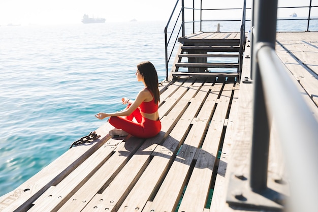 Женщина отдыхает в позе йоги летом на берегу моря