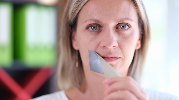 Woman removes adhesive tape covering her mouth concept of freedom of speech human rights and