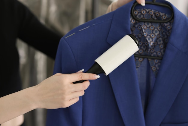 Photo woman removes pellets from blue woolen coat using fabric roller brush young employee takes care