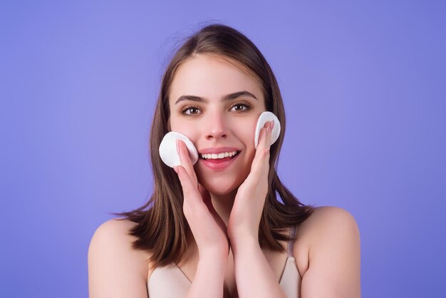 Woman removing makeup with cotton pad near face skin care girl with cotton pad studio isolated backg