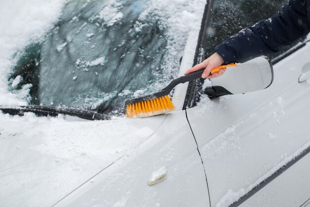 車のフロントガラスから除雪する女性