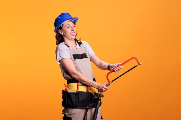 Woman renovating expert holding hand saw and using tool belt,
working on renovation project. building renovator doing carpenter
job with hacksaw and blade to slice, refurbishment work.