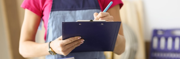 Woman repairman writing paper on clipboard closeup