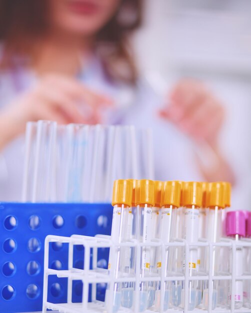 Woman researcher is surrounded by medical vials and flasks isolated on white