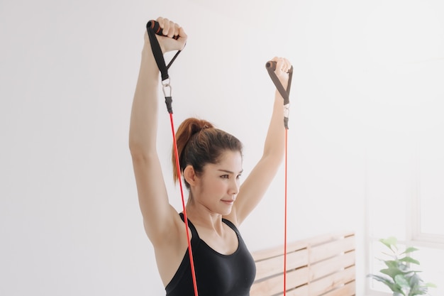 Woman do resistance band upper chest press workout in her bedroom