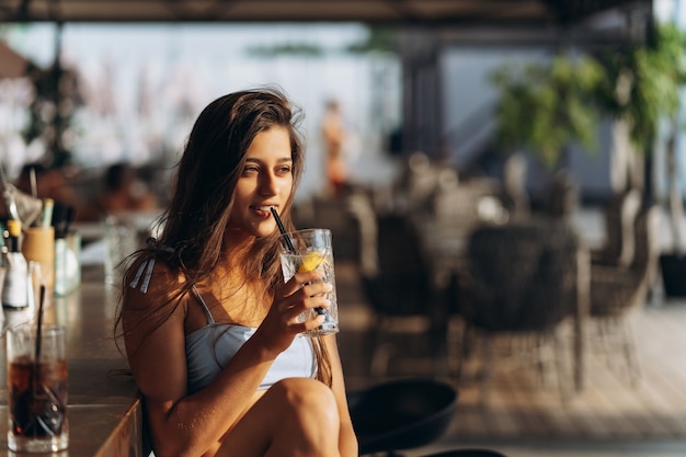 La donna che riposa sul bar della spiaggia beve un cocktail rinfrescante