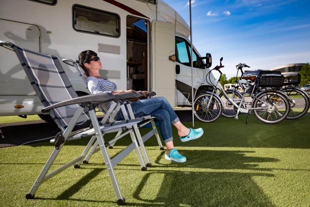 自然の中でキャンプチェアで休んでいる女性。キャラバンカーバケーション。家族旅行、キャンピングカーでの休暇旅行