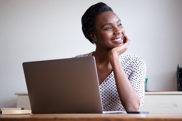 Photo woman resting chin on hand sitting at desk with laptop