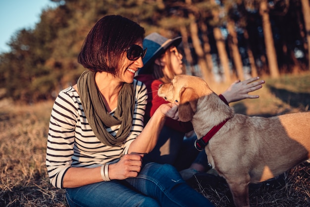 女性は家族と一緒に芝生で休み、彼女の犬を抱きしめる