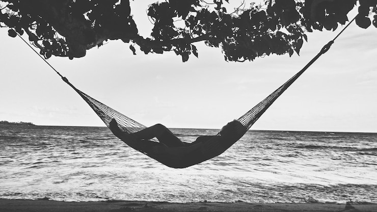 Photo woman resting in hammock over sea against sky