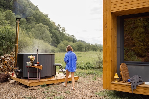 Woman resting on nature in wooden house with hot tub