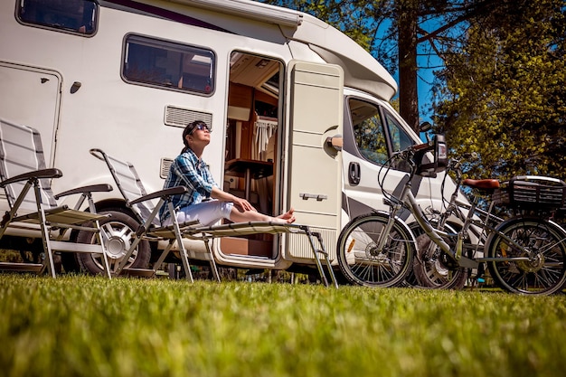 Photo woman resting near motorhomes in nature. family vacation travel, holiday trip in motorhome rv, caravan car vacation.