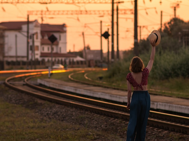 Photo woman in retro hat waving goodbye to the train.