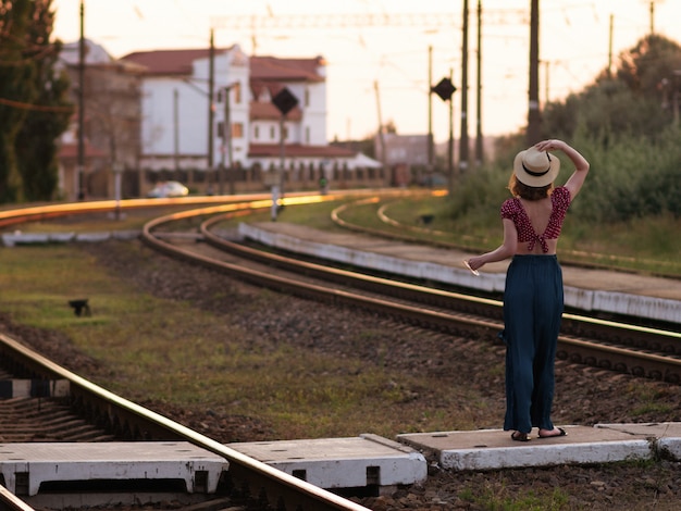 Woman in retro hat waving goodbye to the train.