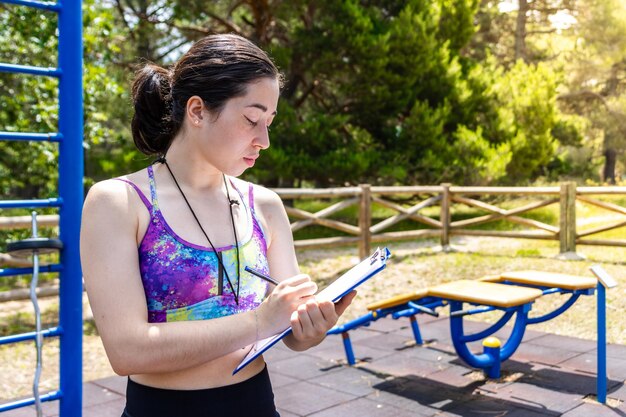 Donna che rivede il piano di fitness in una palestra all'aperto