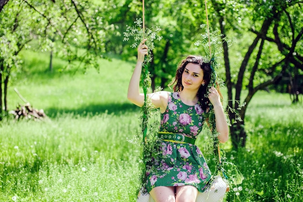 Woman ride on a swing. Green park.