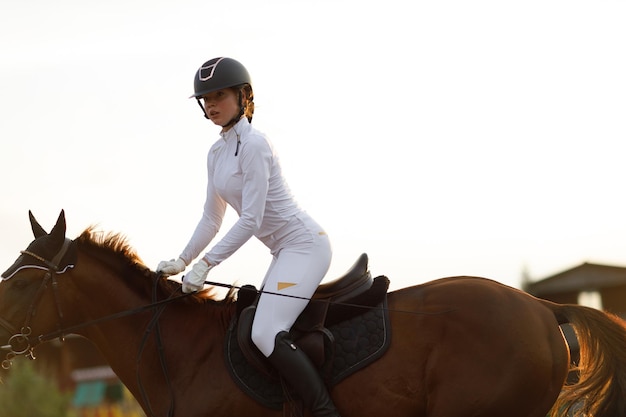 Woman rider jockey in helmet and white uniform preparing horse racing