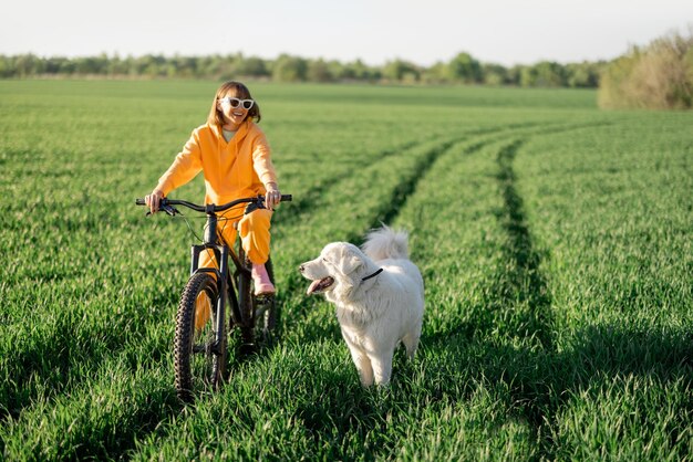 여자는 강아지와 함께 들판에서 자전거를 탄다
