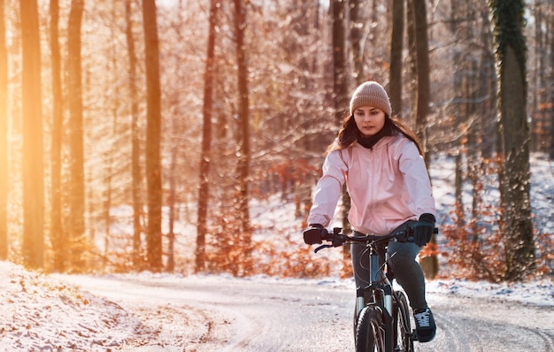 Woman rides a bike in winter Snow and sun weather in the park during outdoor activity Concept of cycling during snowy weather