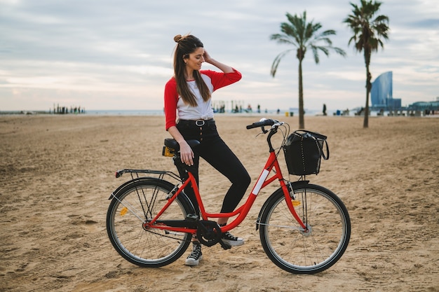 Woman riding bicycle along beach sand at summer time. Healthy and sport concept