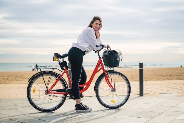 여름 시간에 해변 모래를 따라 자전거를 타는 여자. 건강 및 스포츠 개념