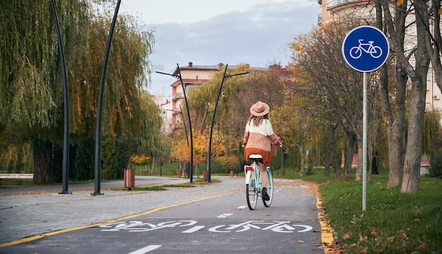 Woman riding bicycle on bike lane in city park